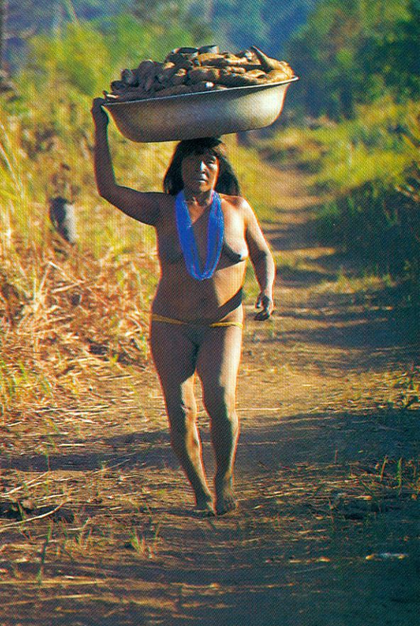 Mulher Mehinaku carregando mandiocas